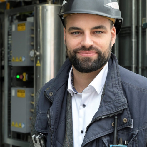 Projektingenieur für die Teilvorhabe des Norddeutschen Reallabors, Marcel Schröder, steht vor der ersten Elektrolyseanlage der Stadtreinigung Hamburg