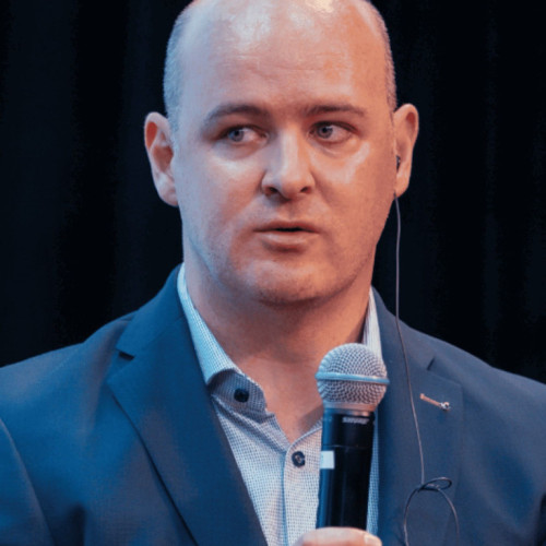 Das Bild zeigt Dr. André Rückert auf einer Konferenz mit einem Mikrofon in der Hand. 
